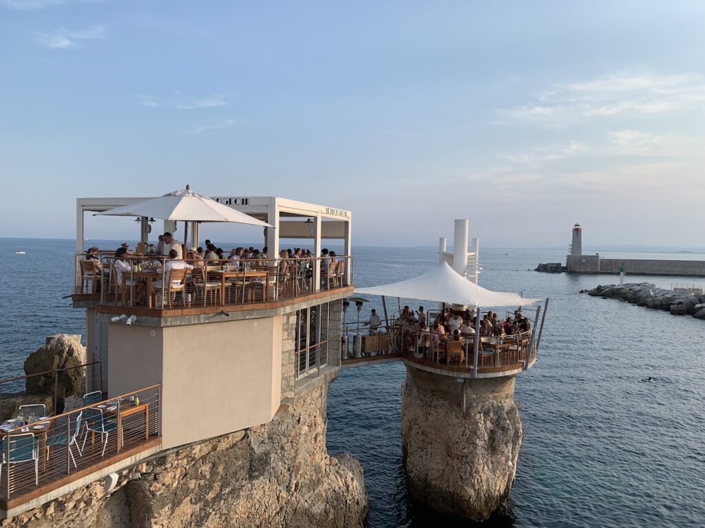 A view of the Plongoir Restaurant in Nice, sticking out on a rocky outcrop above the sea.