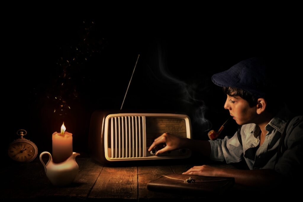 A boy listens to the radio by candelight