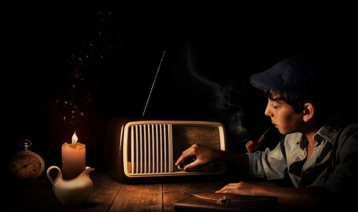 A boy listens to the radio by candelight