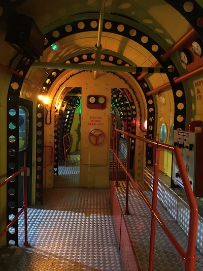 Inside the Yellow Submarine. The walls and oval roof are painted yellow with red railings and handles.