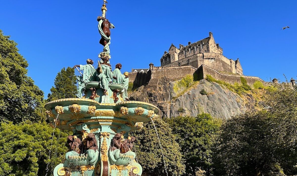 The Ross Fountain shines in the blue sky with Edinburgh Castle in the background