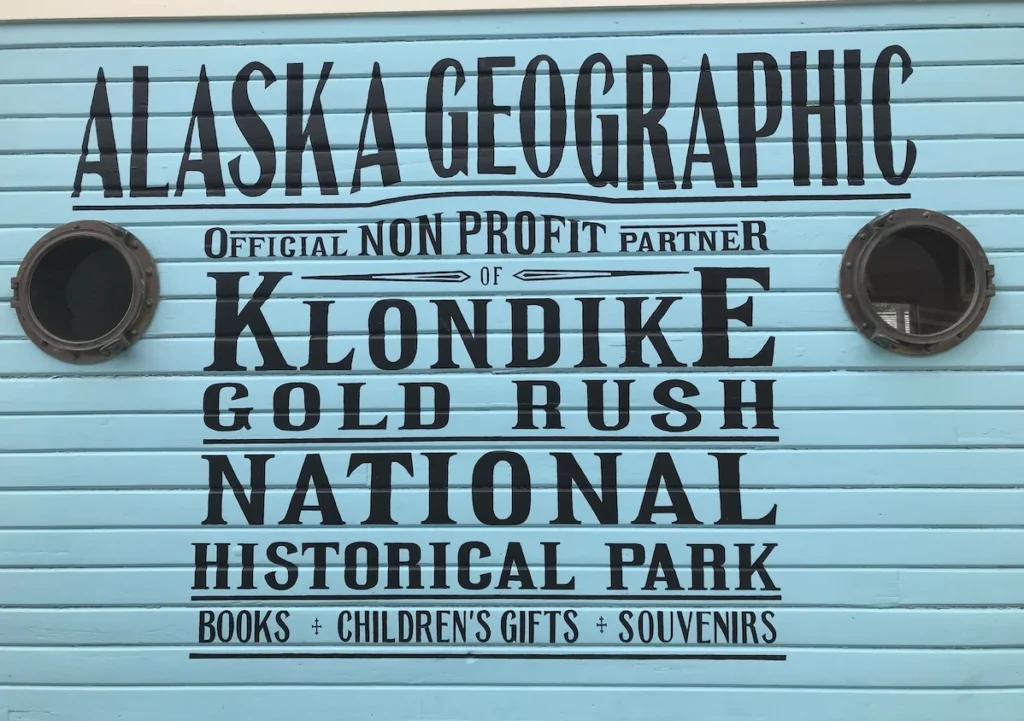 Blue and Black Klondike National Park Sign on a building wall in Skagway