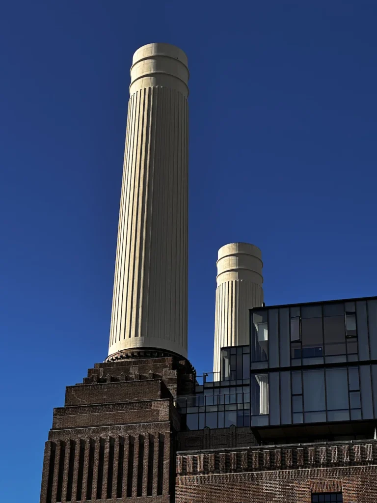 Two of the iconic Battersea Power Station Chimneys against a clear blue sky