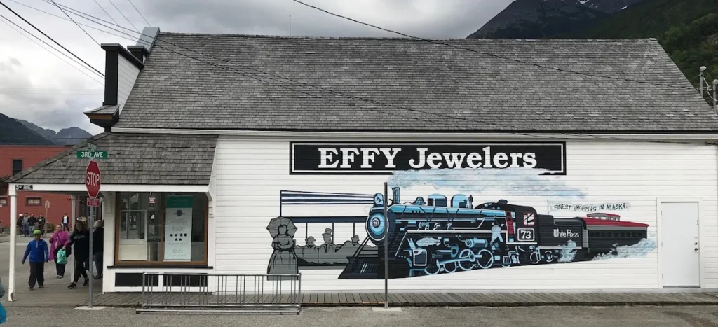 A grey wooden building of Effy Jewellers with a large painted mural of a steam locomotive, Skagway Alaska