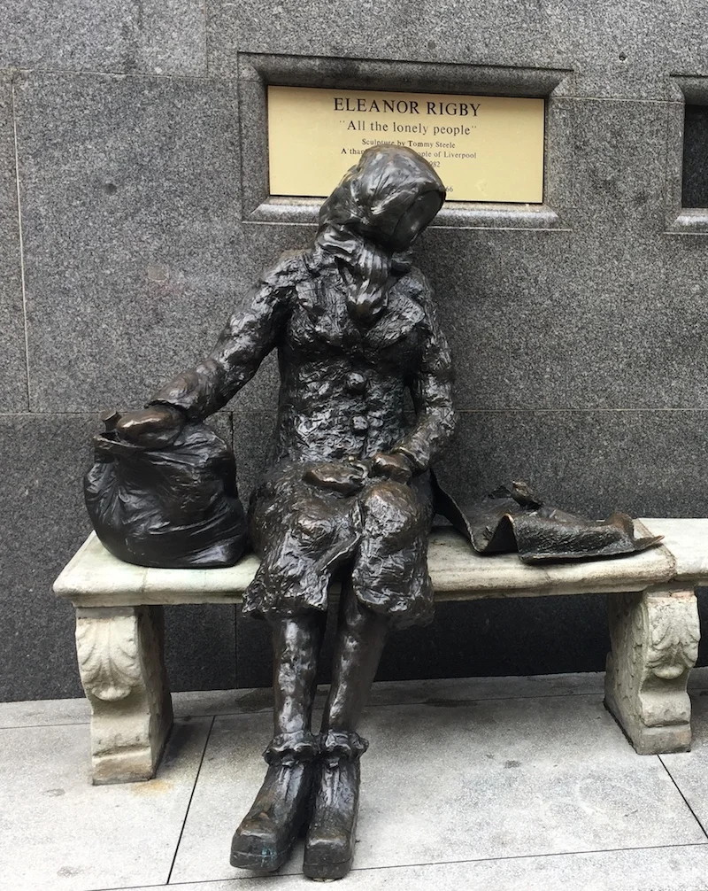 A statue of 'Eleanor Rigby sits on a stone bench in Liverpool.