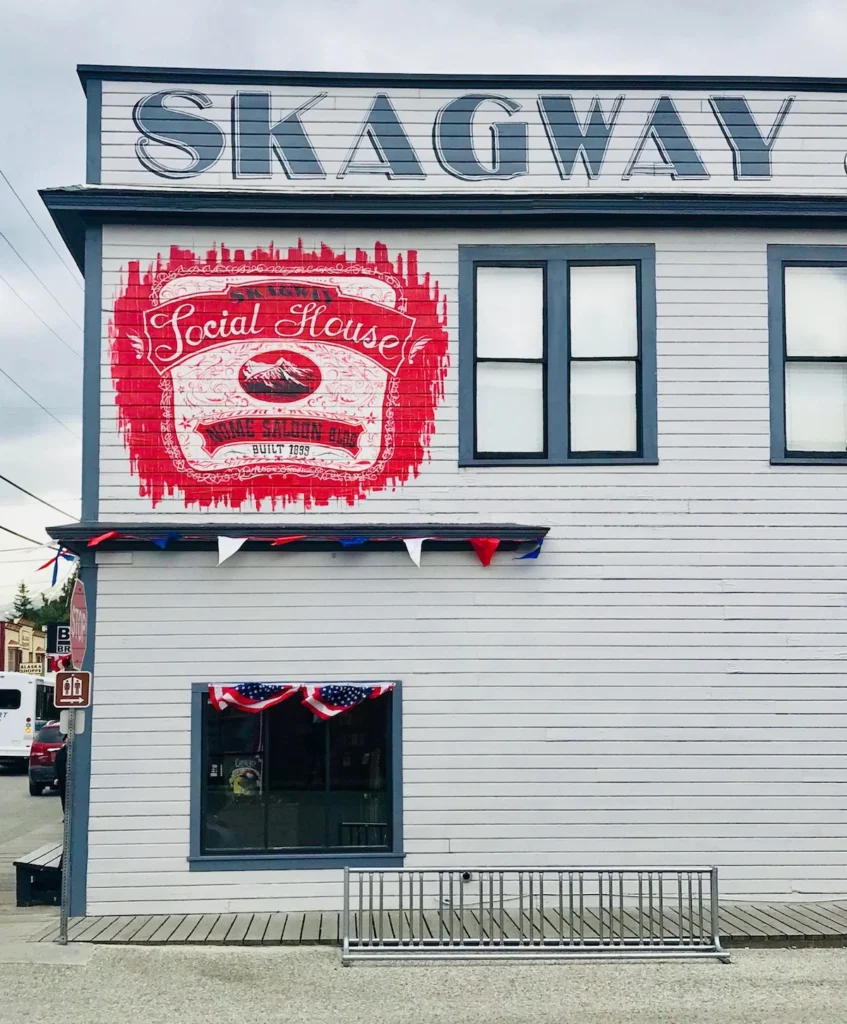 A grey looking building with a bright red mural advertising a local bar
