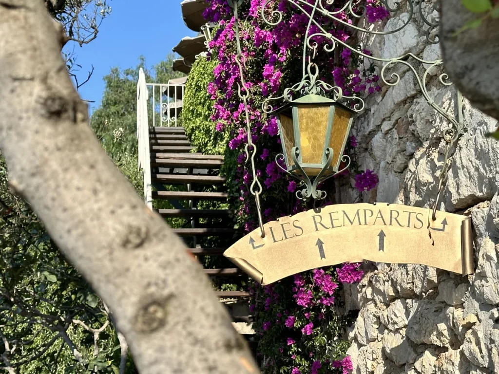 A golden sign points the way to the Les Ramparts restaurant in Eze