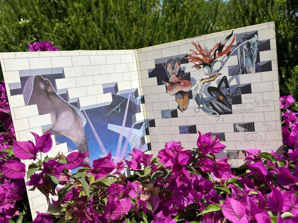 The open gatefold of Pink Floyd's The Wall album pictured against bright flowers in the South of France