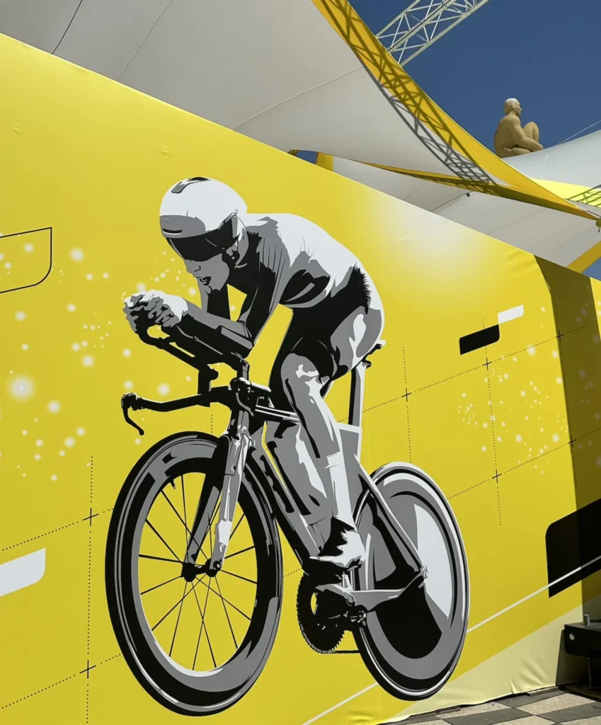 A yellow tour de France hoarding in the bright sunshine of Nice 2024