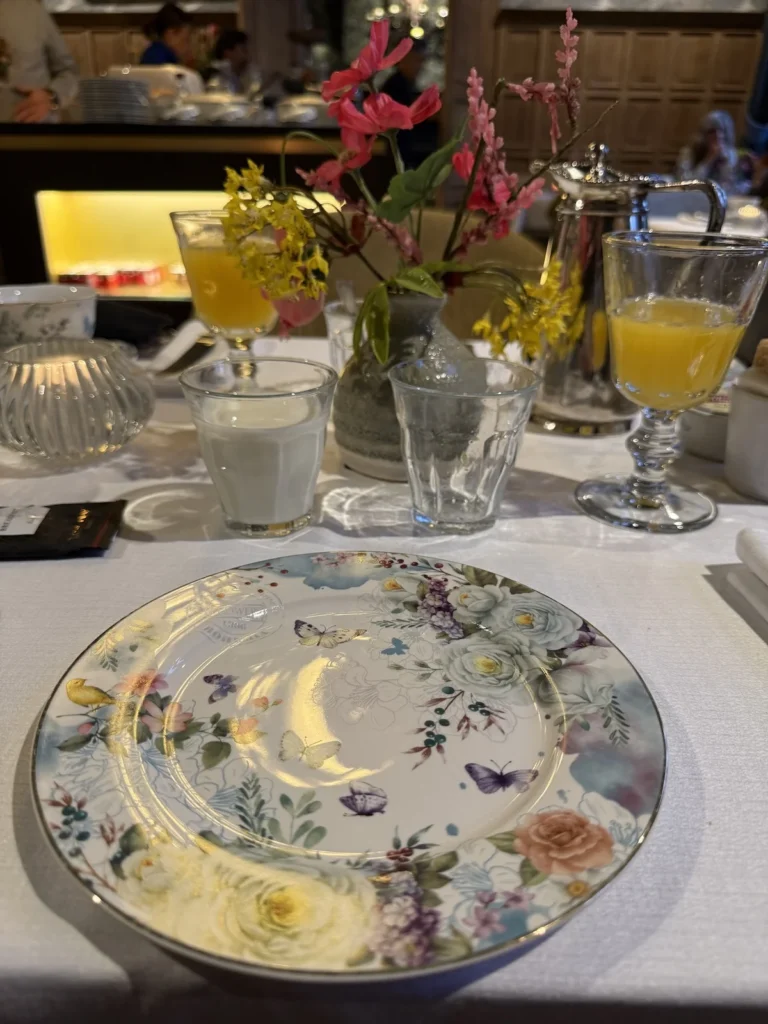 A beautiful round plate stands in front of a chunky glass goblet of fresh orange juice in the dining room of the Orangerie Hotel