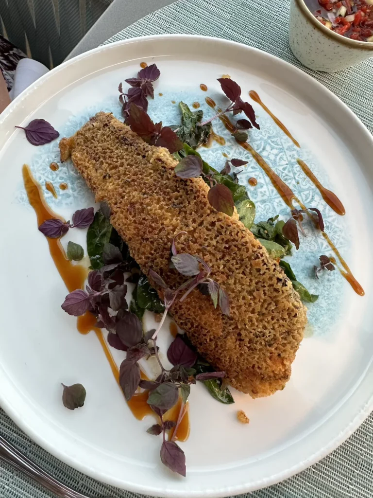 A beautiful brown dish sits upon a bed of vegetables on a white plate