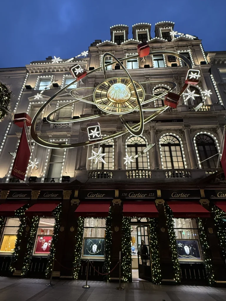 The Cartier Store on London's Bond Street has a large gold planet surrounded by orbits and stars above it's tree adorned front 