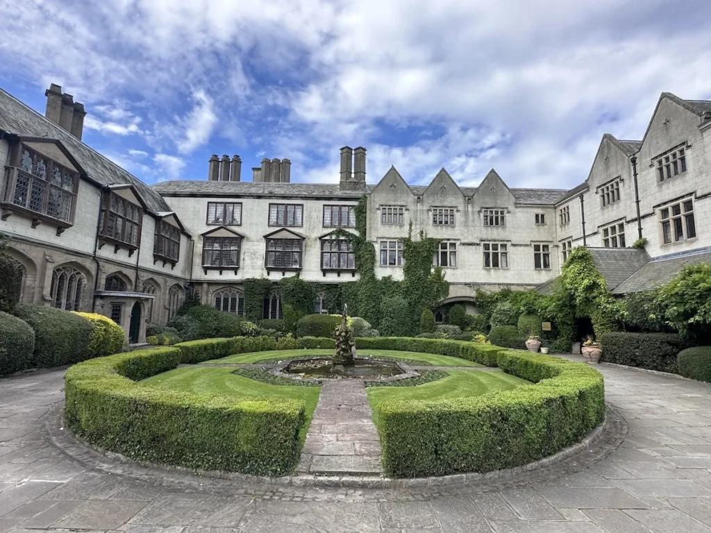 The horse hose circular drive of Coombe Abbey Hotel entrance . The hotel buildings frame a circular green hedge and grass with fountain in the middle