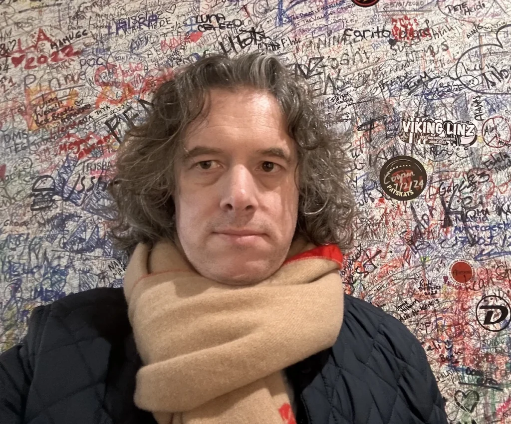 The author against a graffiti covered wall in Liverpool