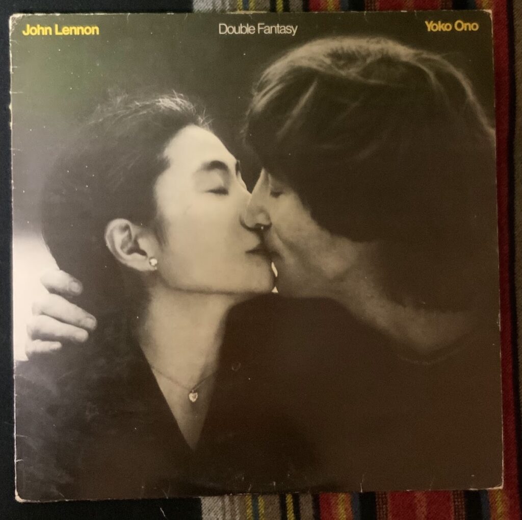 The Front Cover of John and Yoko's album Double Fantasy showing Yoko on the left leaning into John on the right kissing her