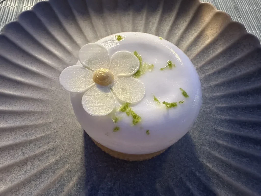 A delicate white flower style desert sits on a grey plate.