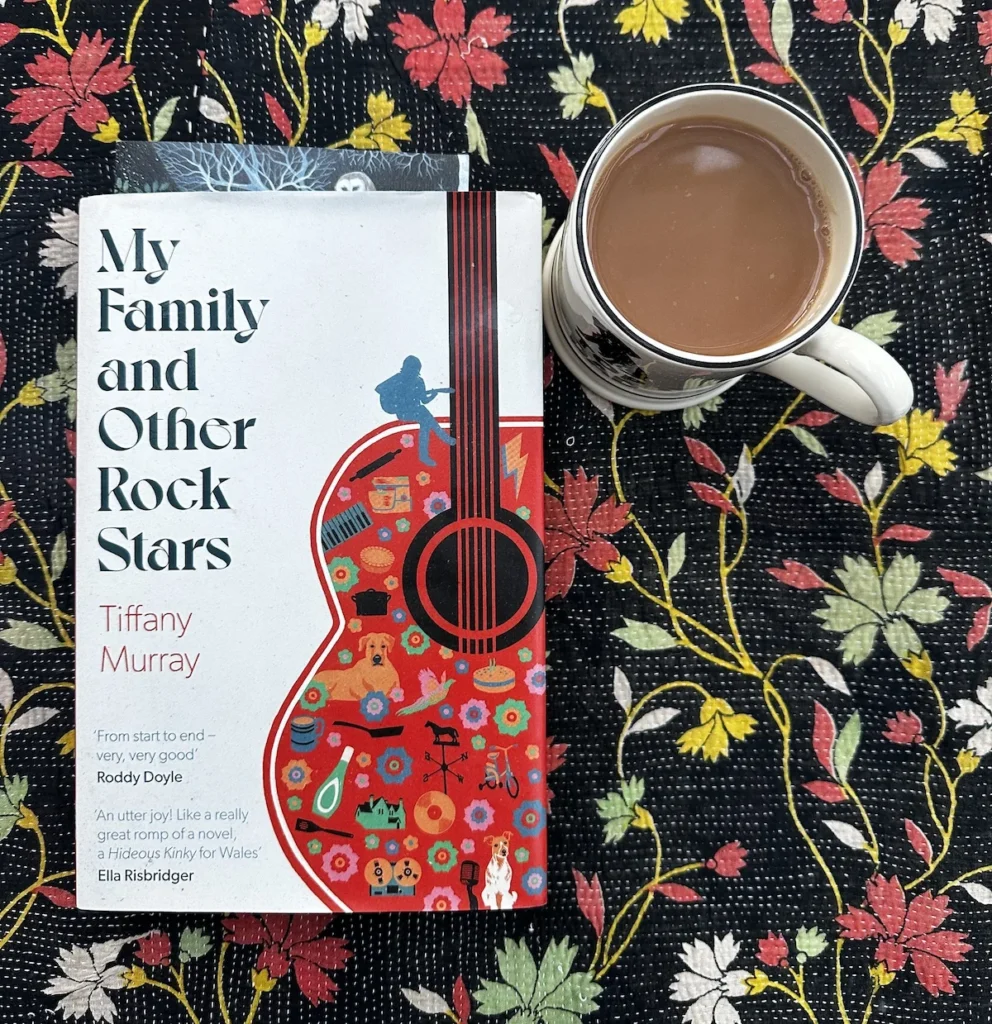 A top down photograph of a Christmas gift book of ;my family and other rock stars' with an Emma Bridgewater mug of tea