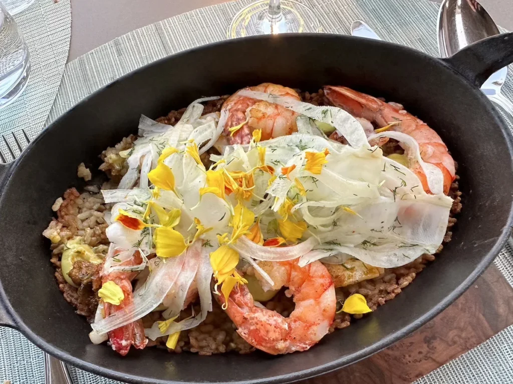 Large Gambas prawns sit atop a rice dish served in a small pan style dish