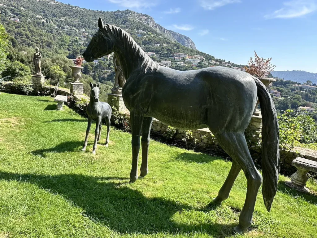 A large horse and foal statue stand on green grass in the Chèvre D'Or garden.