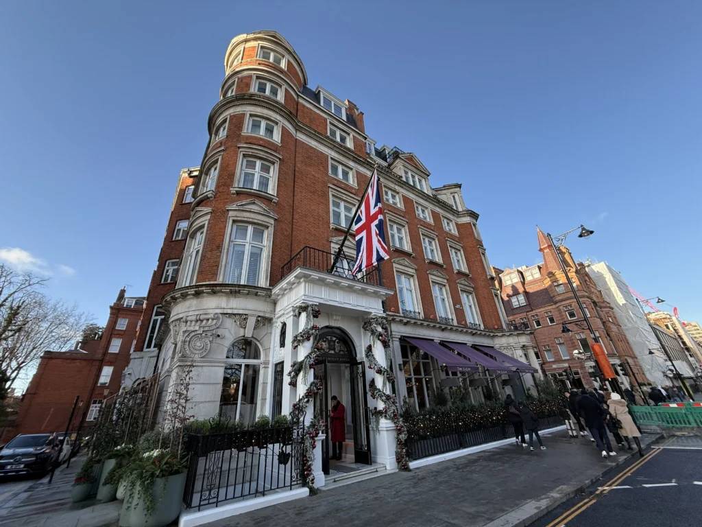 The Exterior of the Belmond Cadogan Hotel against a blue sky with the Union Jack flag flying above the door