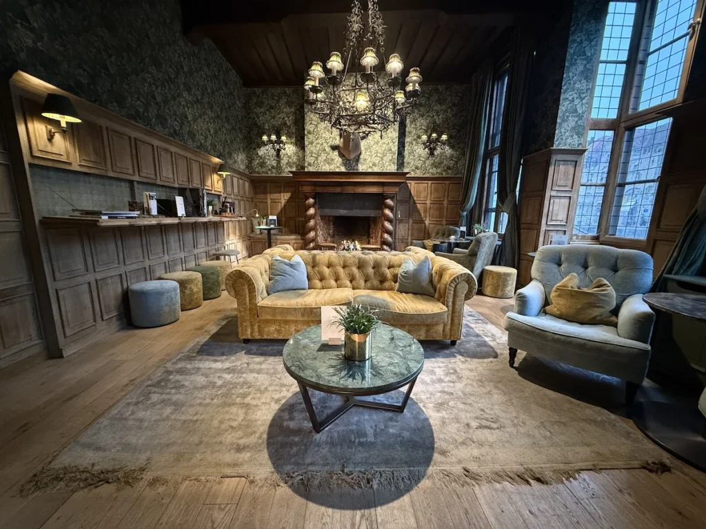 A soft yellow sofa stands in the middle of a wood panelled lunge room at the Hotel Orangerie in Bruges