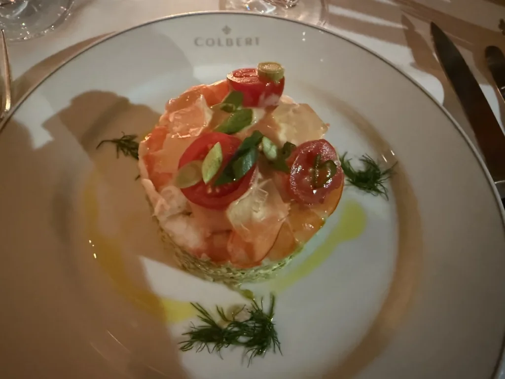 A white Colbert crested plate showcases a 'stack' of avocado and fresh prawns