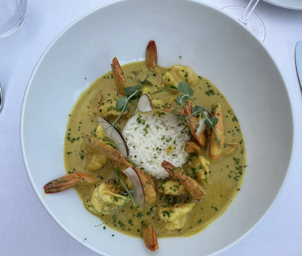 A rich prawn curry surrounds a neat pile of white rice in a round white bowl