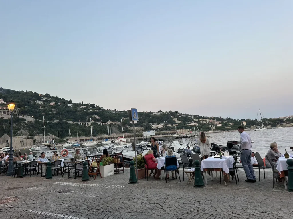 The street and tables next to the water at Mère Germain restaurant in Villefranche