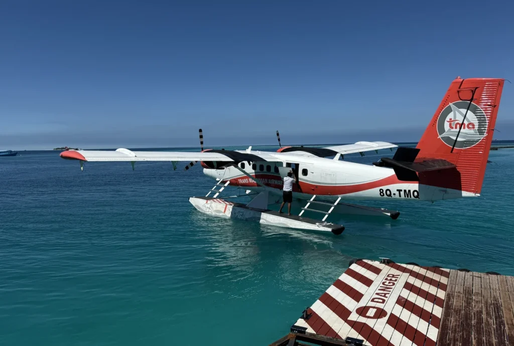 The Trans Maldivian Airline Twin Otter Plane in its distinctive white and red livery on the turquoise Maldive Sea