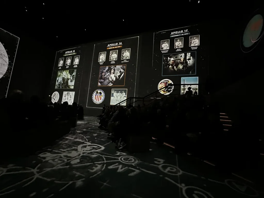 A screen showing the badges and crew members from Apollo 15, Apollo 16 and Apollo 17.