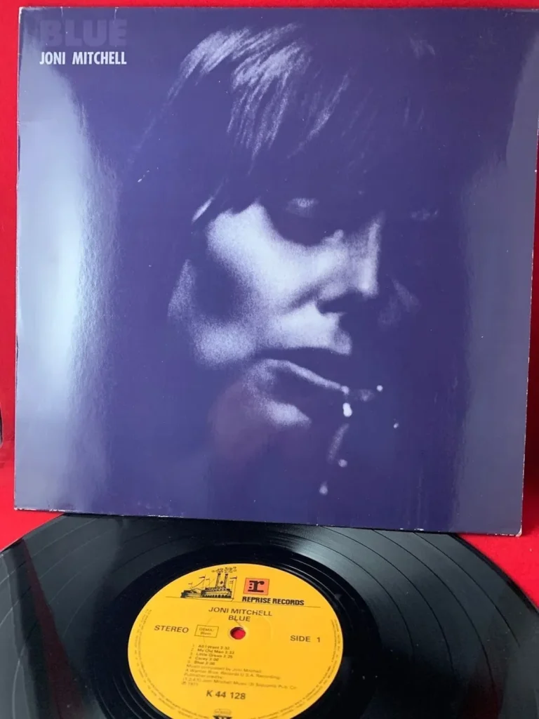 The blue cover of Joni Mitchell's classic album sits above the black vinyl with yellow record label on a red base.