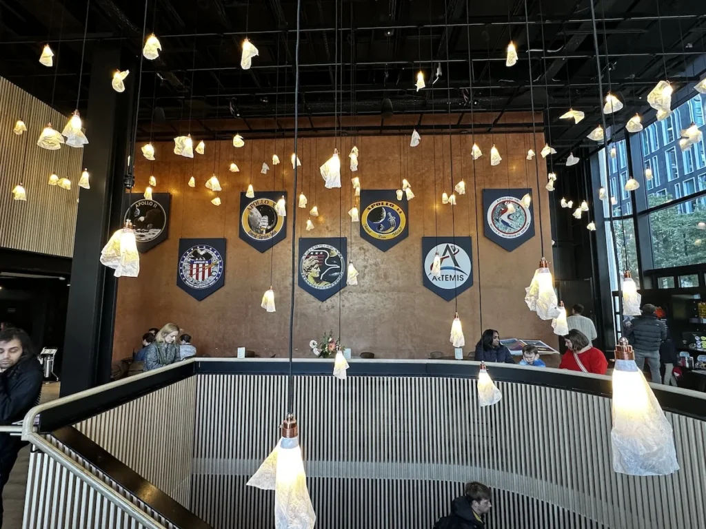 The cafe wall at Lightroom with Mission badges for NASA missions including Artemis