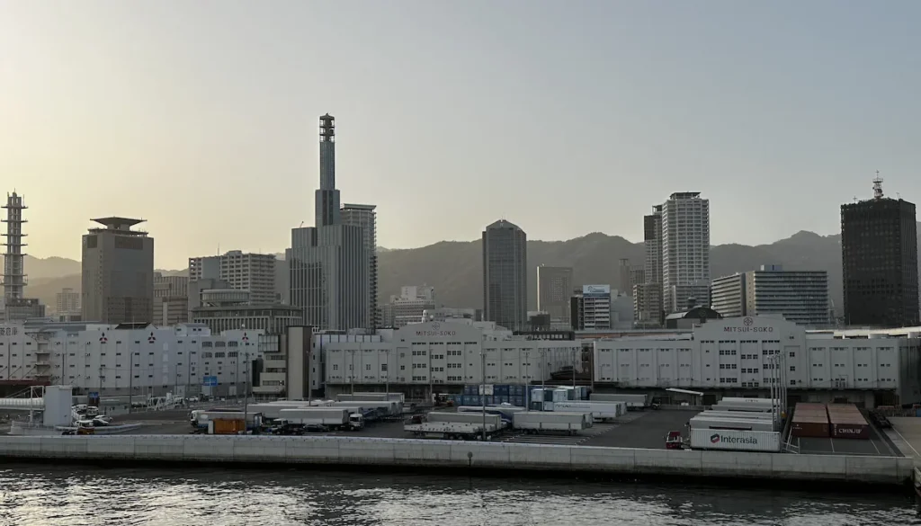 A view of Kobe Port’s waterfront, showcasing modern architecture and historic port structures along the bay. The area blends maritime heritage with contemporary design, highlighting Kobe’s significance as an international shipping hub. © Wine Travel and Song.
