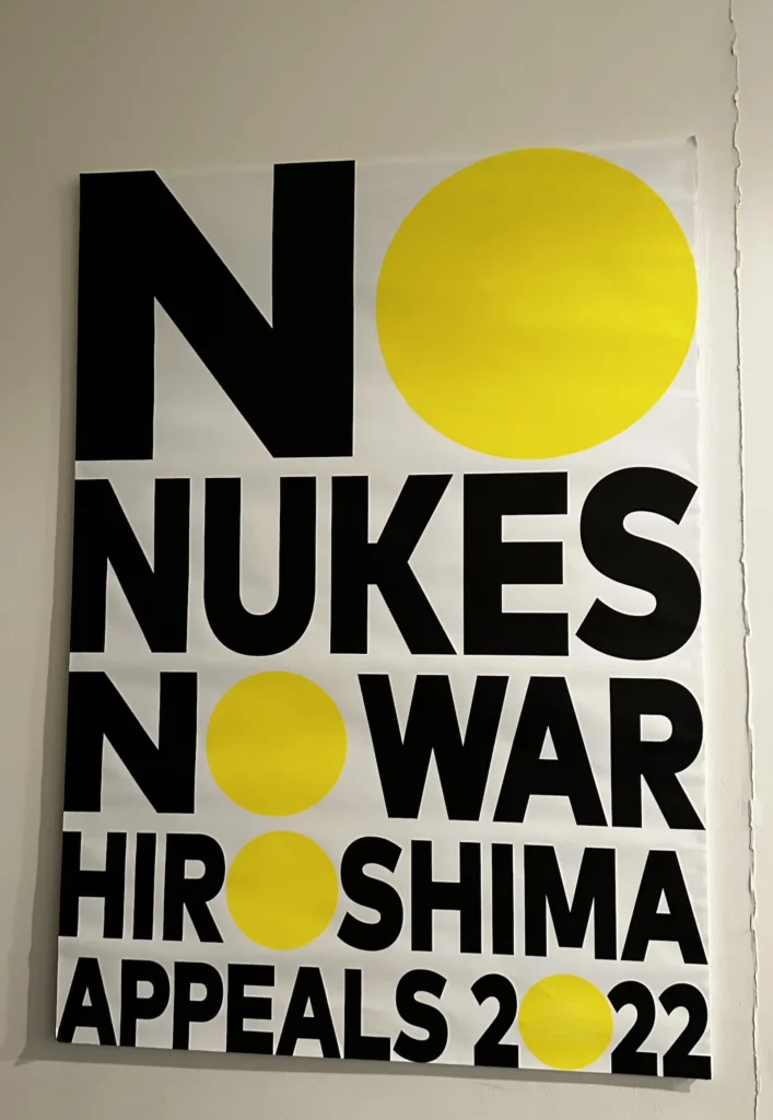 a Bold black and yellow anti-nuclear poster reading No Nukes No War Hiroshima Appeals 2022 ©Wine, Travel & Song
